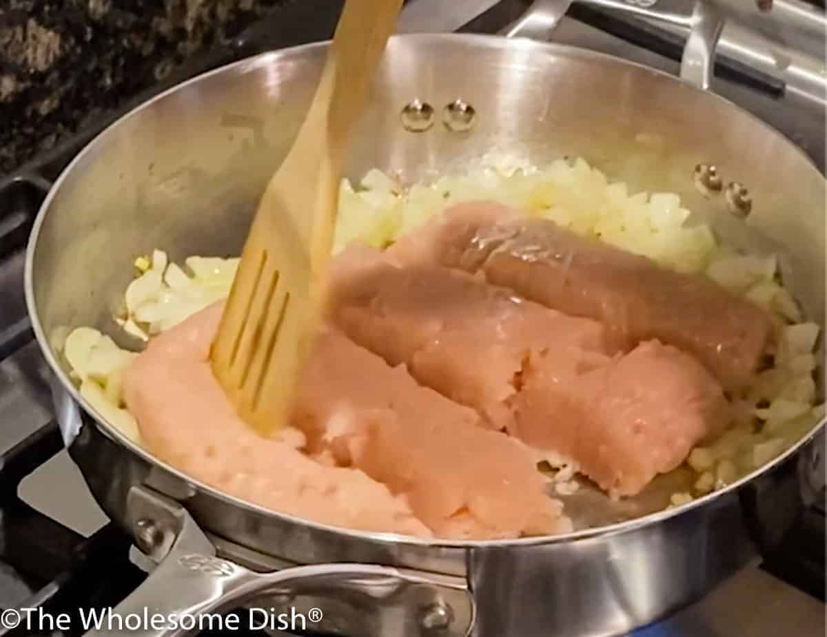 Ground chicken being broken apart in a skillet.