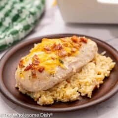 chicken breast on a bed of rice covered in cheese and bacon pieces.