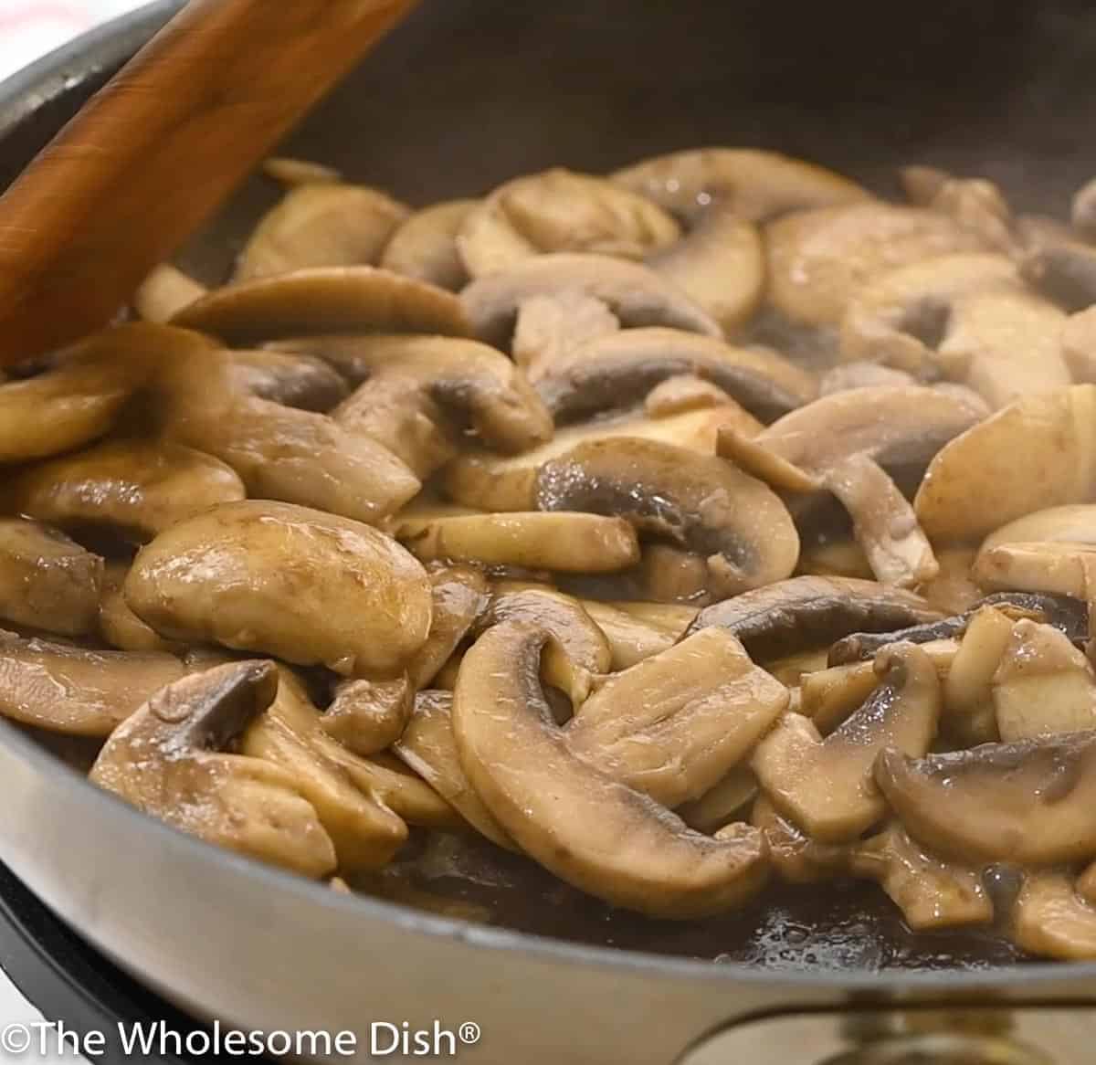 Skillet full of mushrooms sautéed in butter and oil.