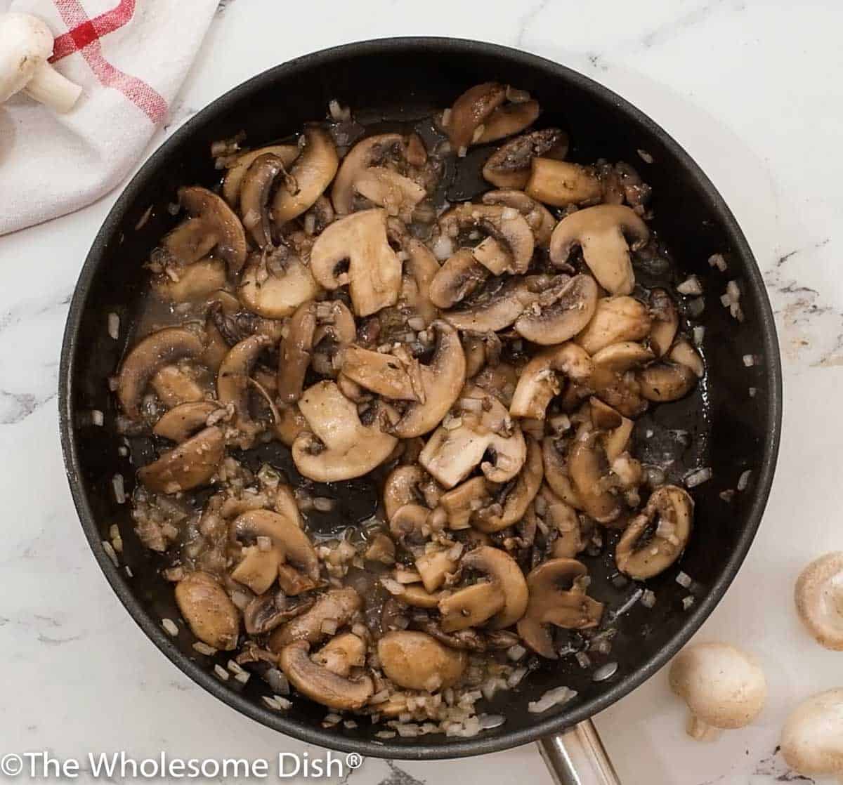 Skillet full of cooked mushroom and onion sauce for spaghetti.