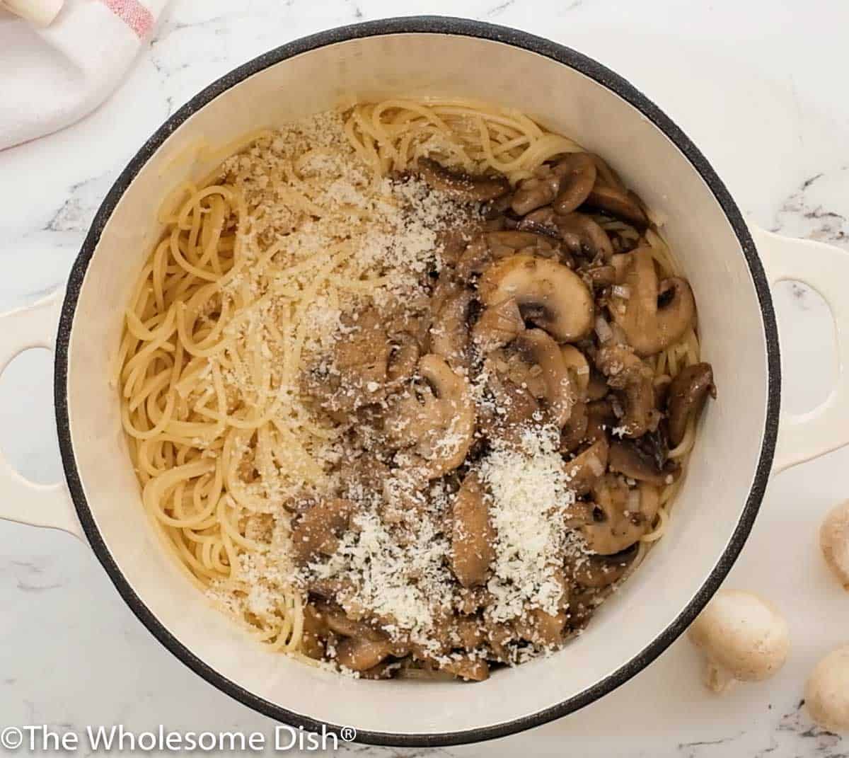 Large pot full of pasta, mushroom sauce, and parmesan.