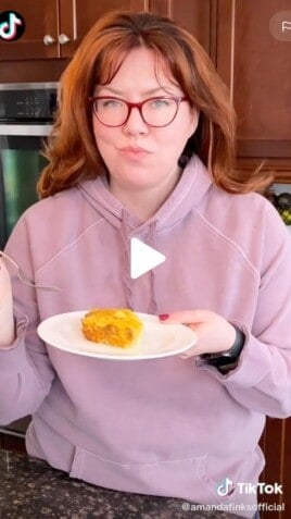 Woman holding a plate of breakfast casserole.