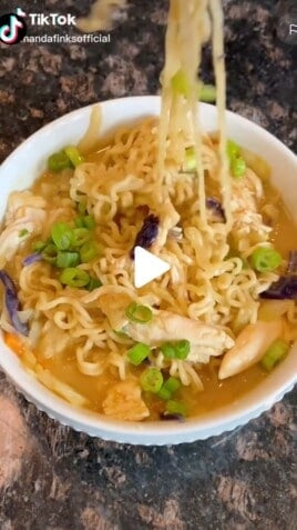 Bowl full of ramen with chicken and green onions.
