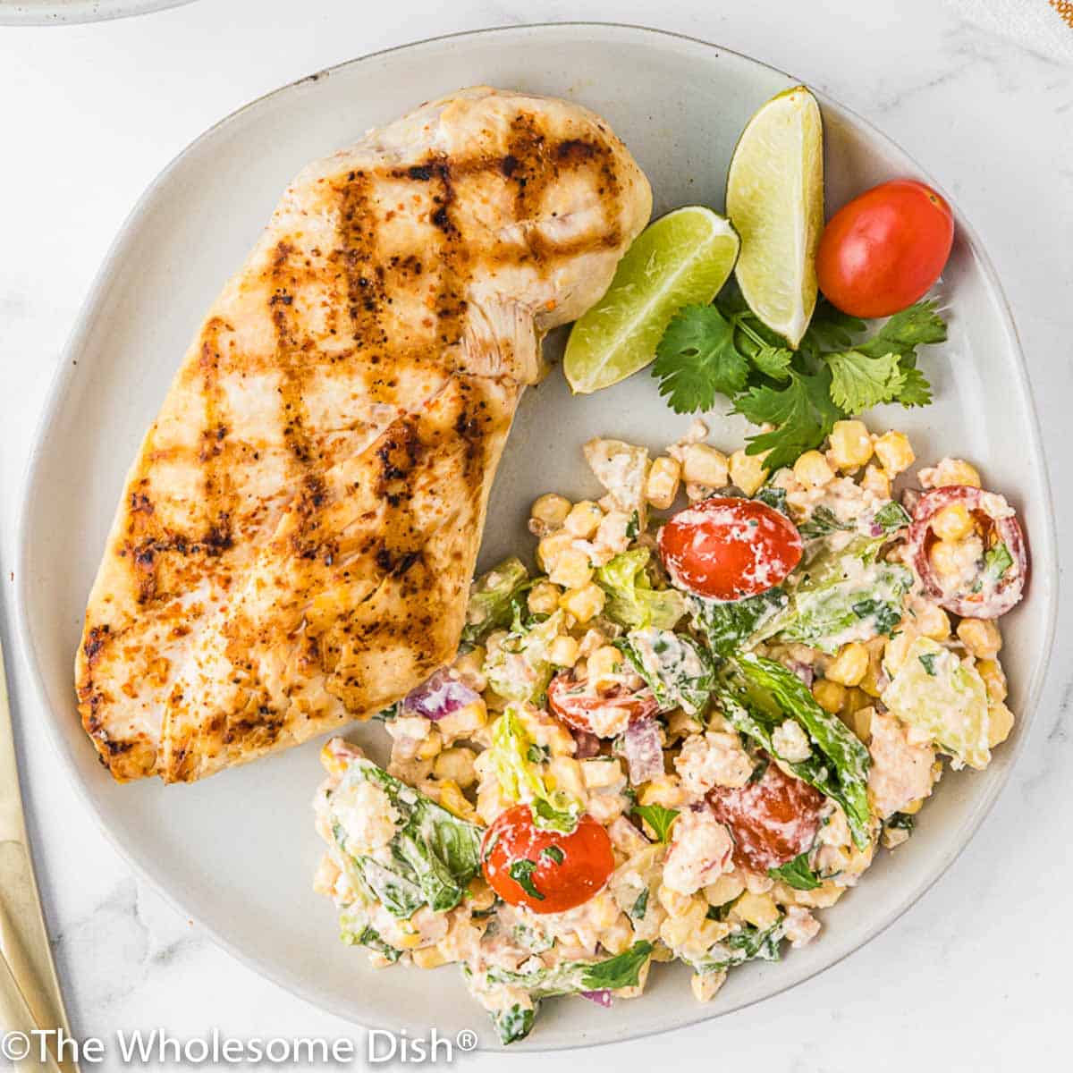Plate with grilled chicken and Mexican street corn chopped salad.