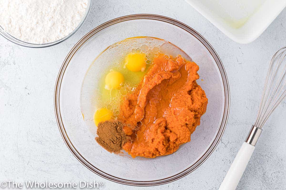 Eggs, pumpkin puree, oil, and cinnamon in a whisking bowl.