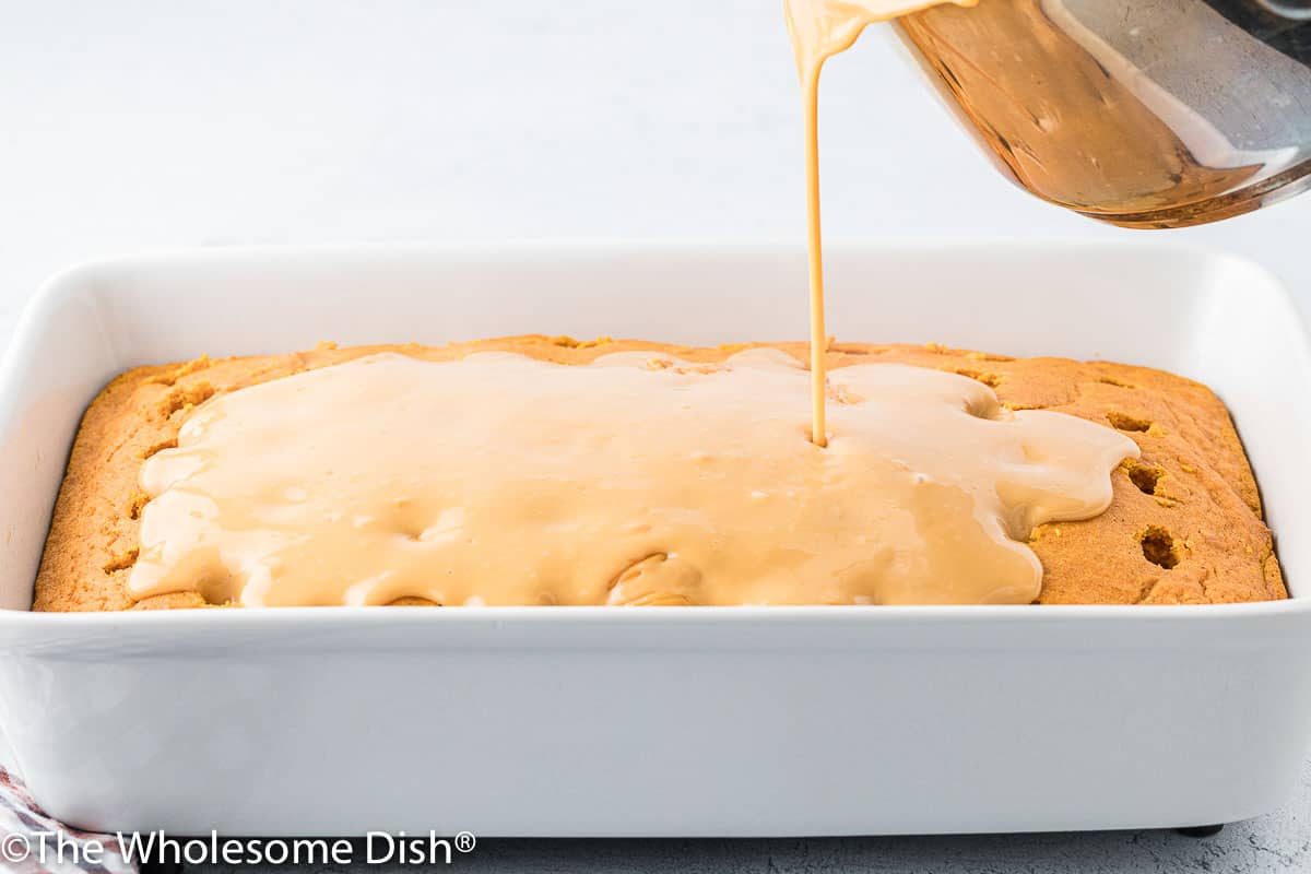 Pouring butterscotch pudding over a pumpkin poke cake.