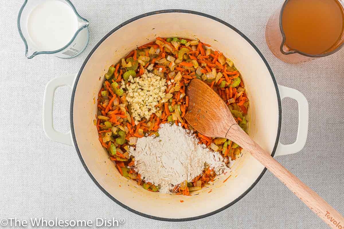 Adding seasoning, garlic, and flour to the veggies in the pot.