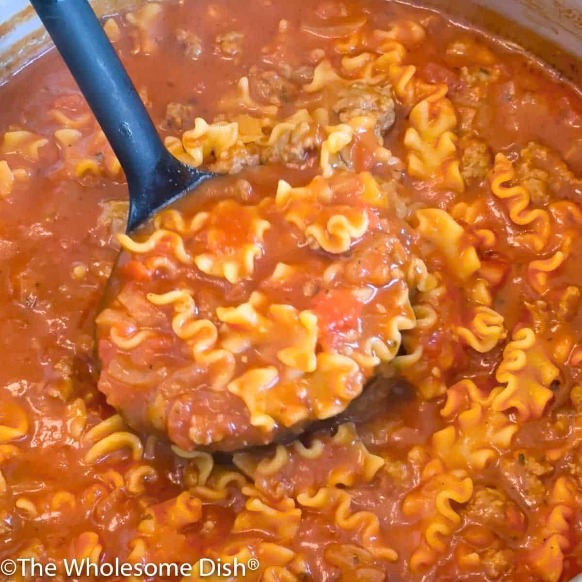 Ladle full of lasagna soup being pulled up out of the pot.