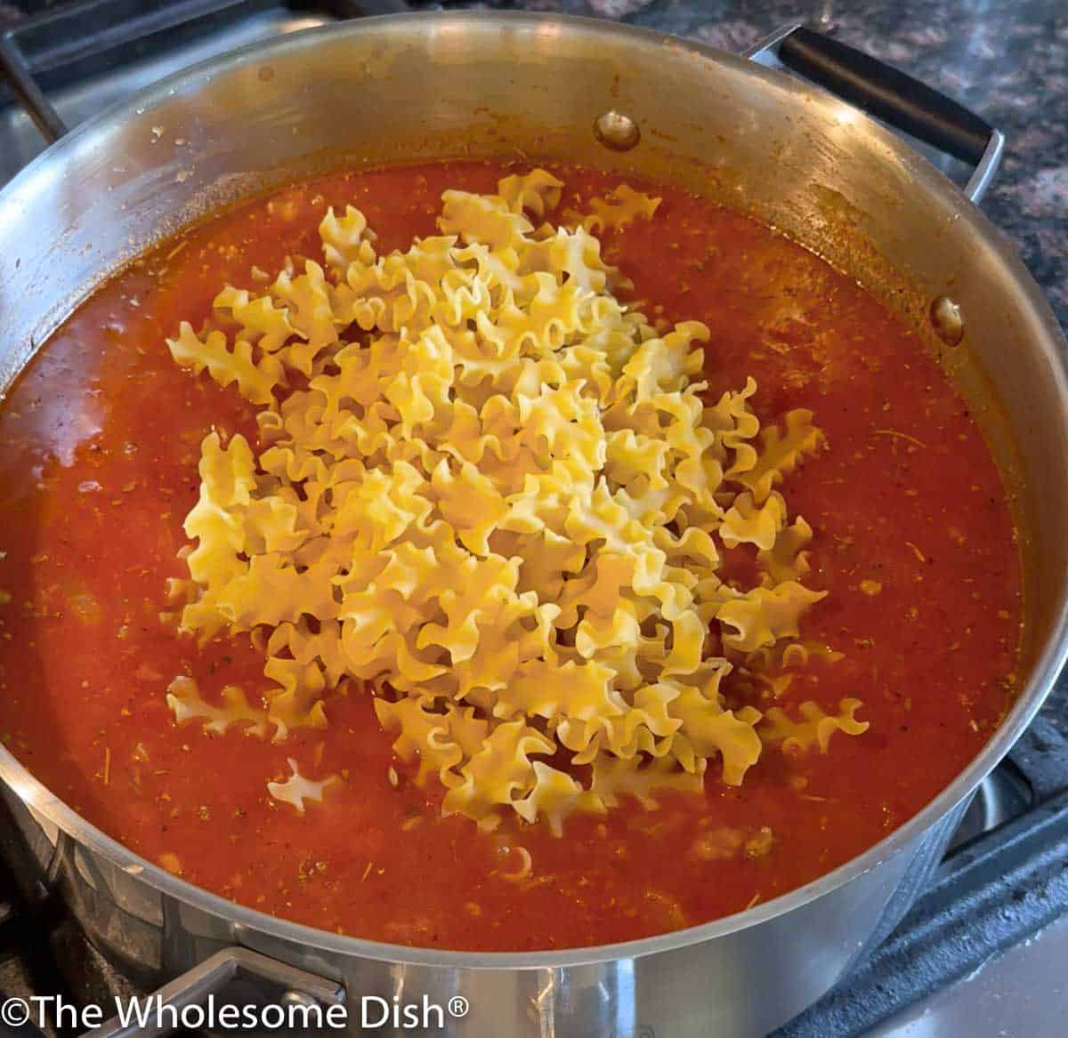 Mini lasagna noodles being added to the pot.