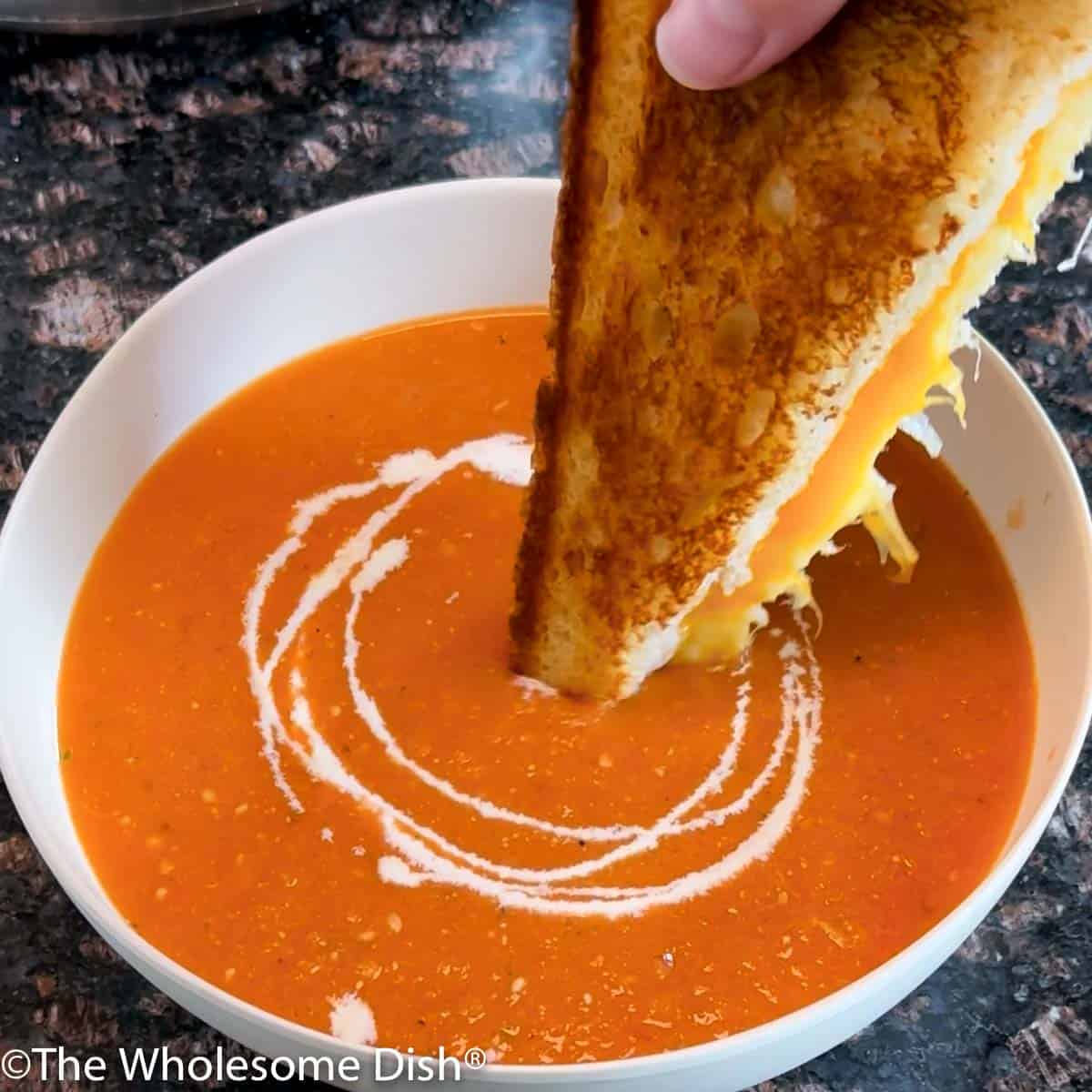 Dipping a grilled cheese into a bowl of tomato soup.
