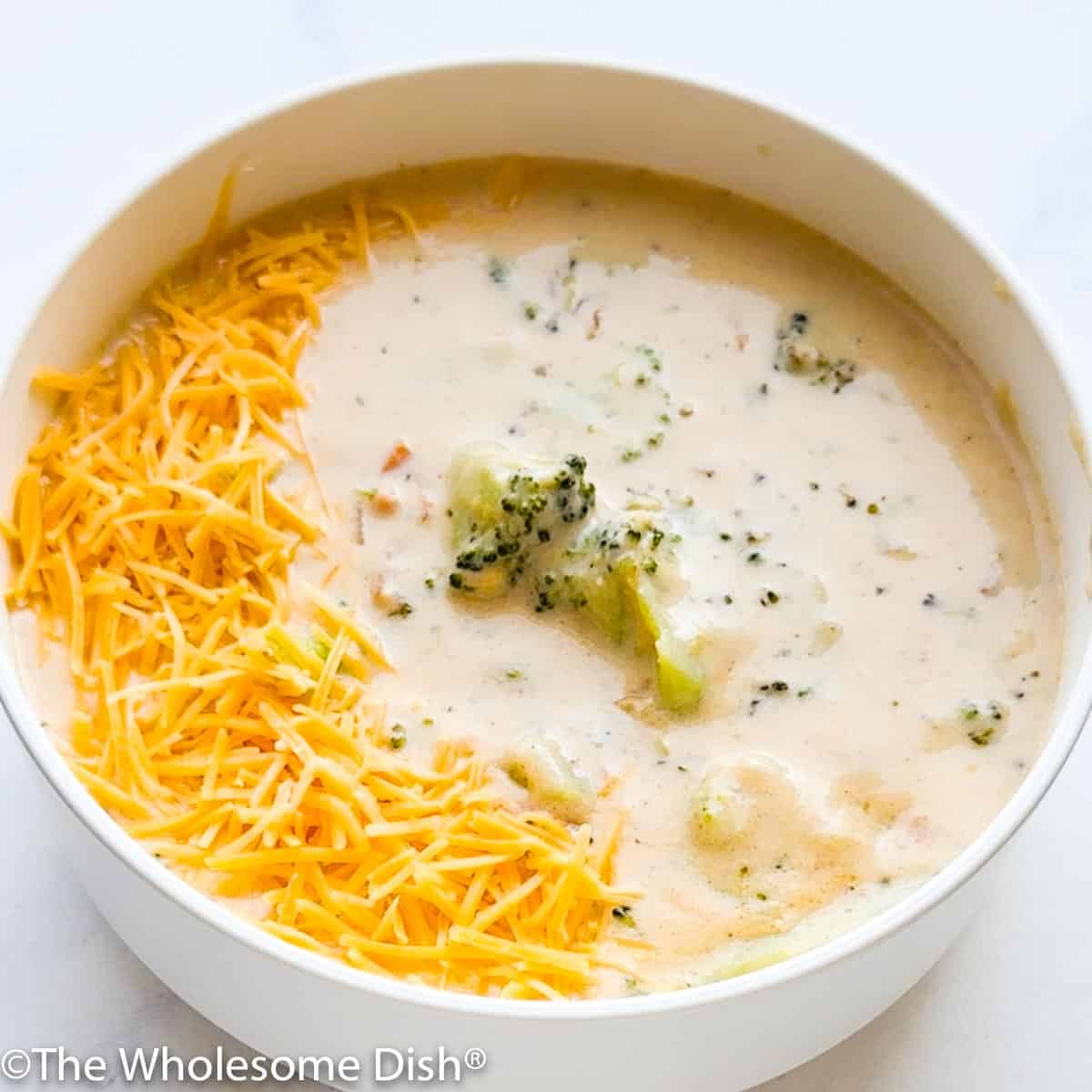 White bowl full of broccoli cheese soup.