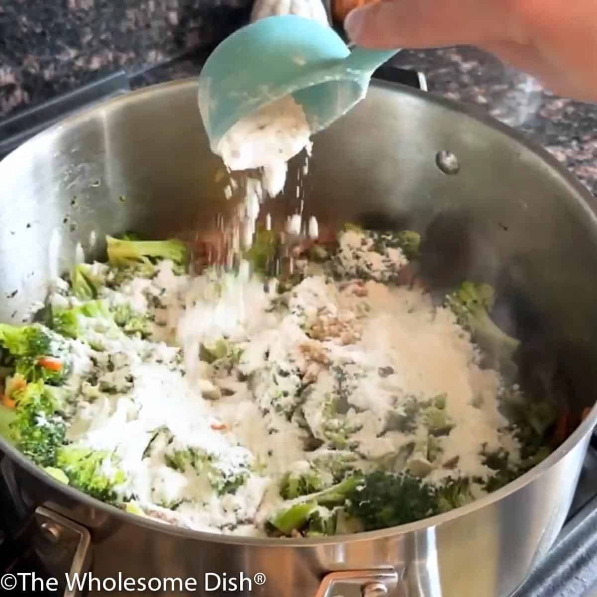 Adding flour to the soup pot full of vegetables.