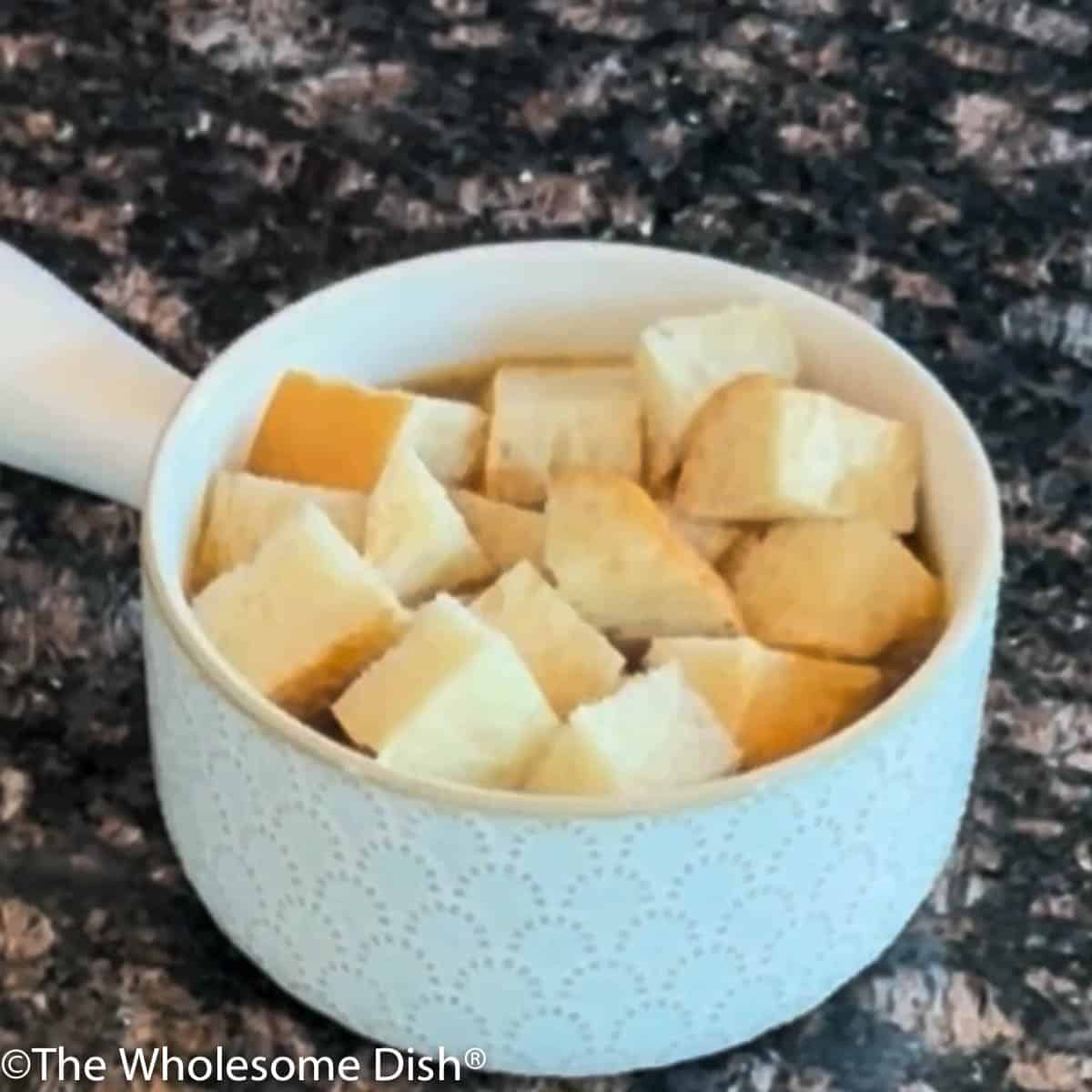 Chopped bread on top of a bowl of French onion soup.