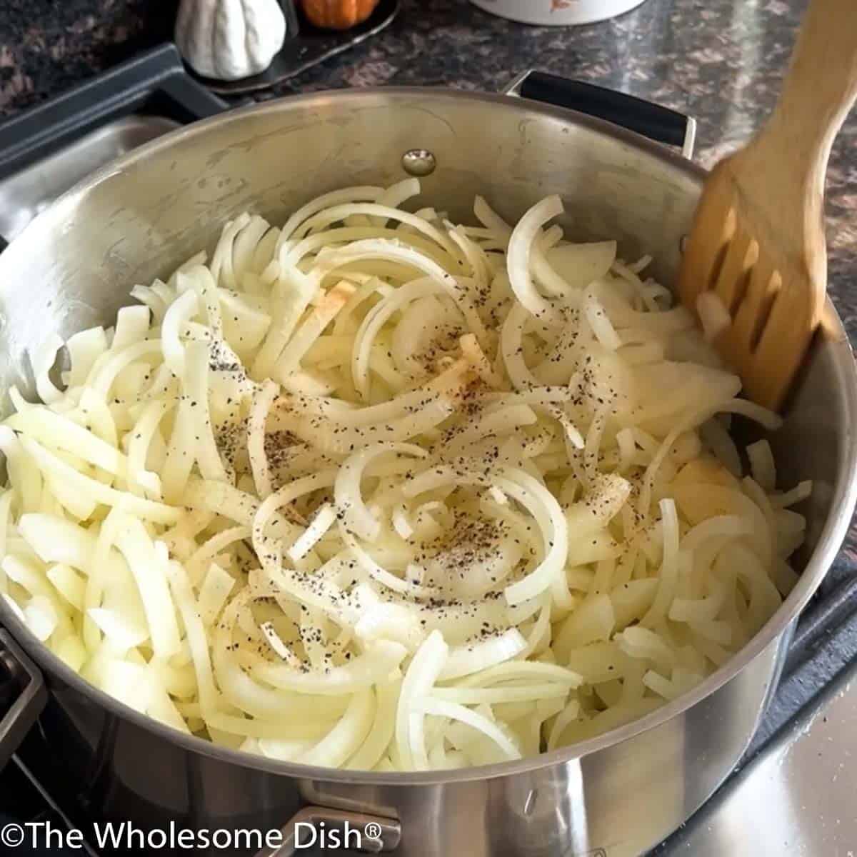 Sliced onions cooking in a large soup pot.