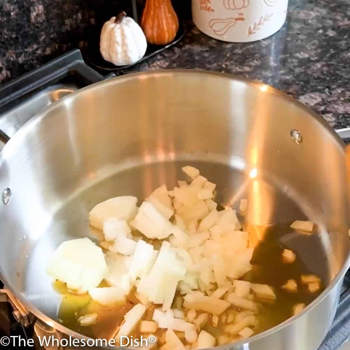 Adding chopped onions to olive oil in a large soup pot.