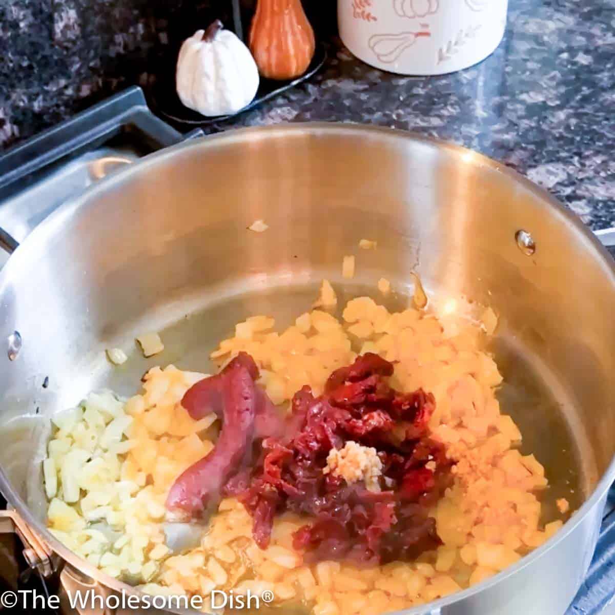 Adding sun dried tomatoes, minced garlic, and tomato paste to the pot.