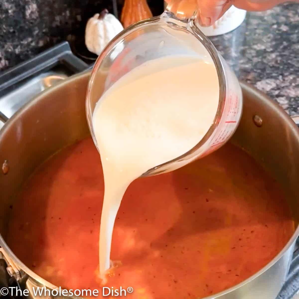 Adding chicken broth and whole milk to the pot.