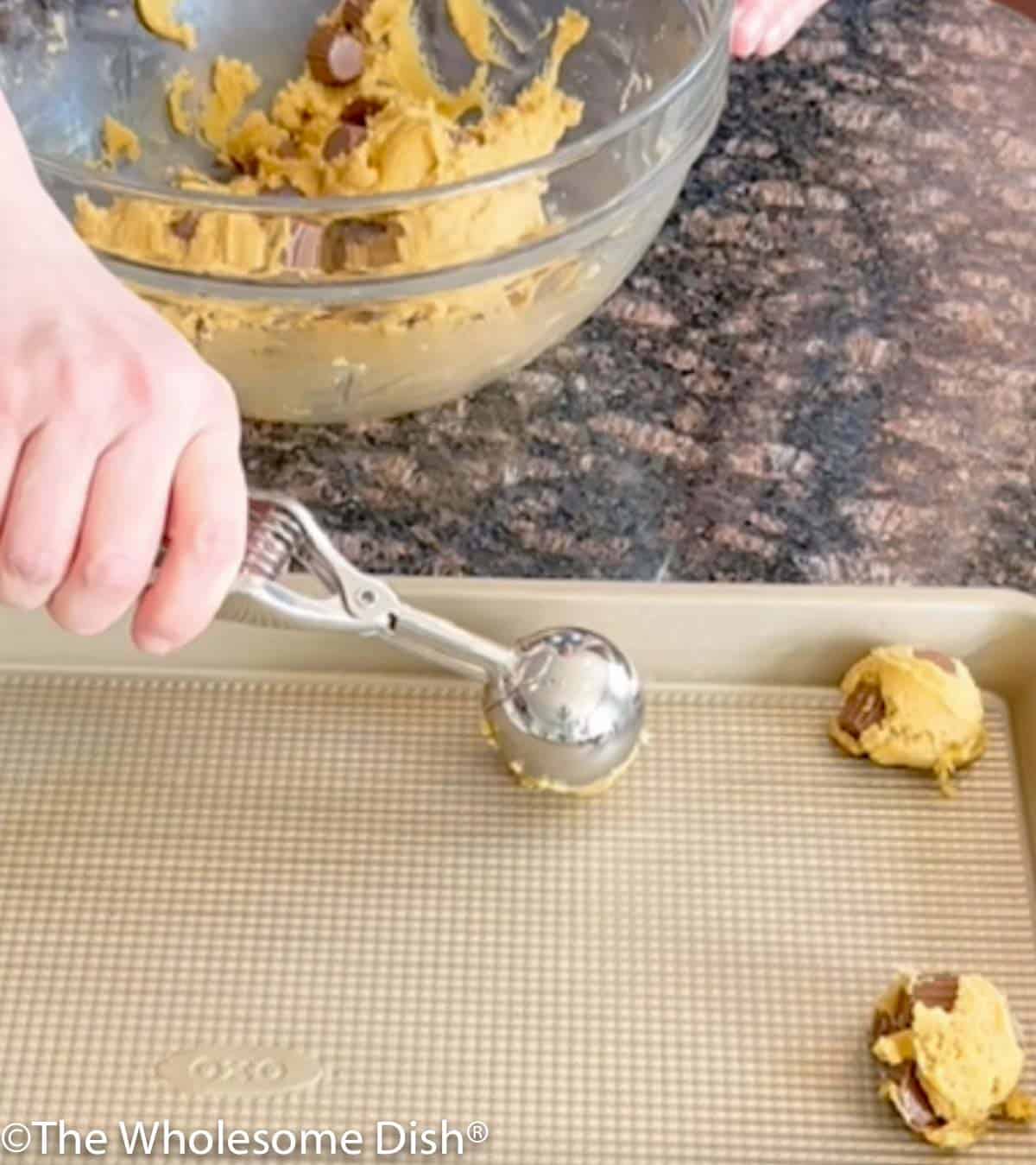 Scooping cookie batter onto a cookie sheet.