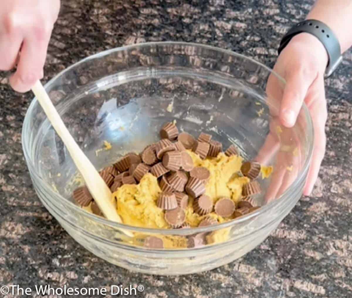 Stirring mini peanut butter cups into the cookie batter.
