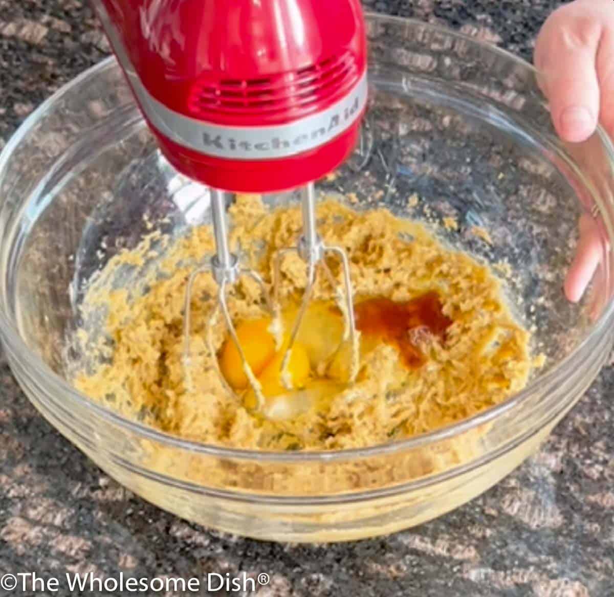 An egg and vanilla being mixed into the bowl.