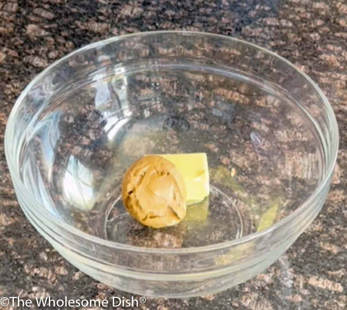 Butter and peanut butter in a large glass mixing bowl.