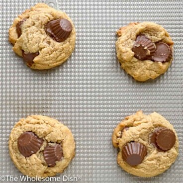 Four peanut butter cup cookies on a baking sheet.