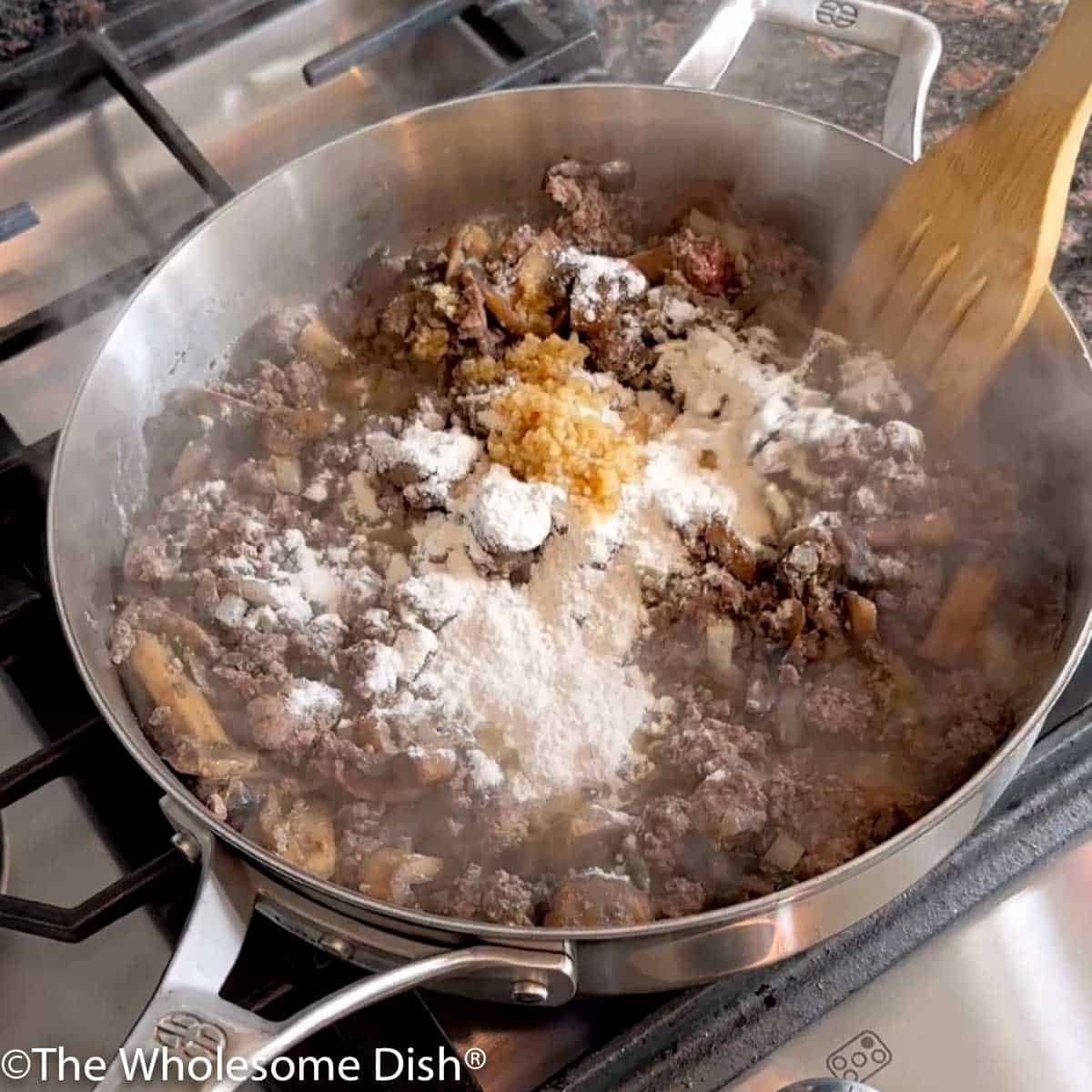 Flour and minced garlic added to the skillet.