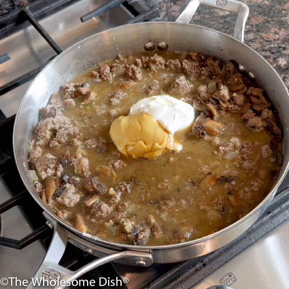 Beef broth, sour cream, Dijon mustard, and Worchestershire sauce added to the skillet.