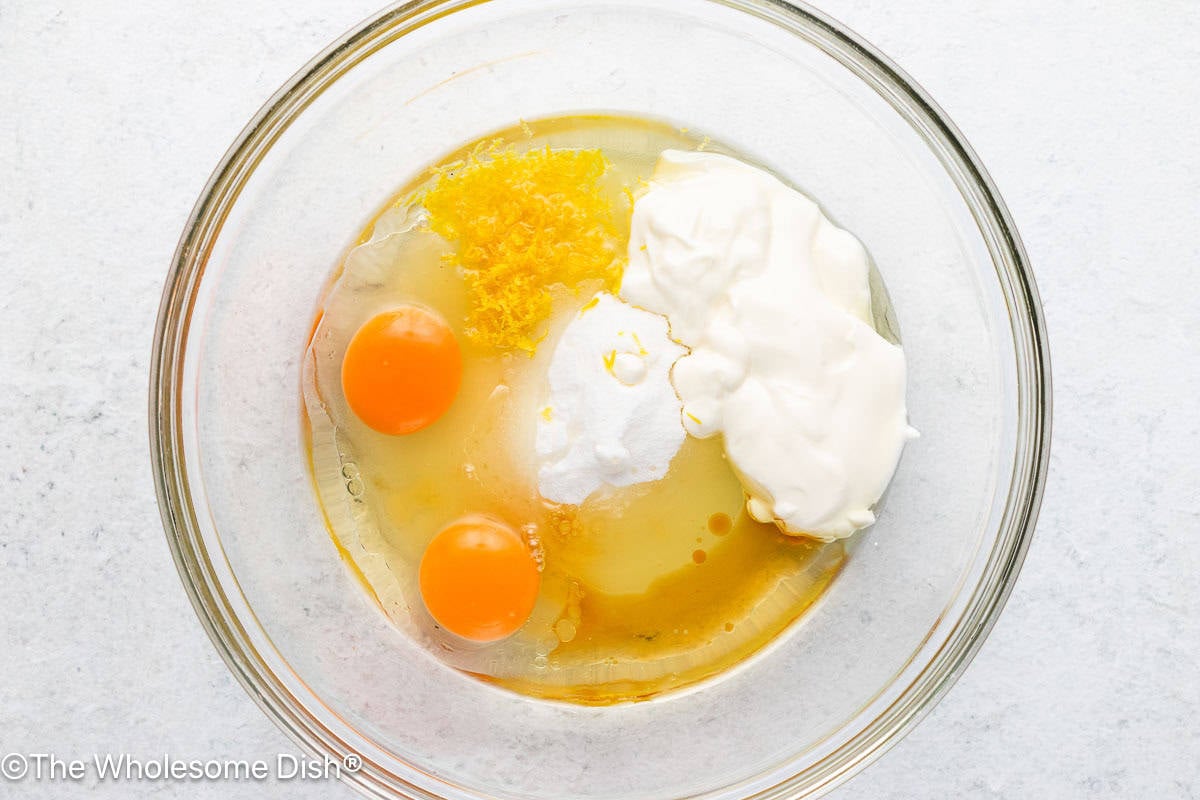 Mixing bowl full of sugar, eggs, olive oil, lemon zest, and vanilla.