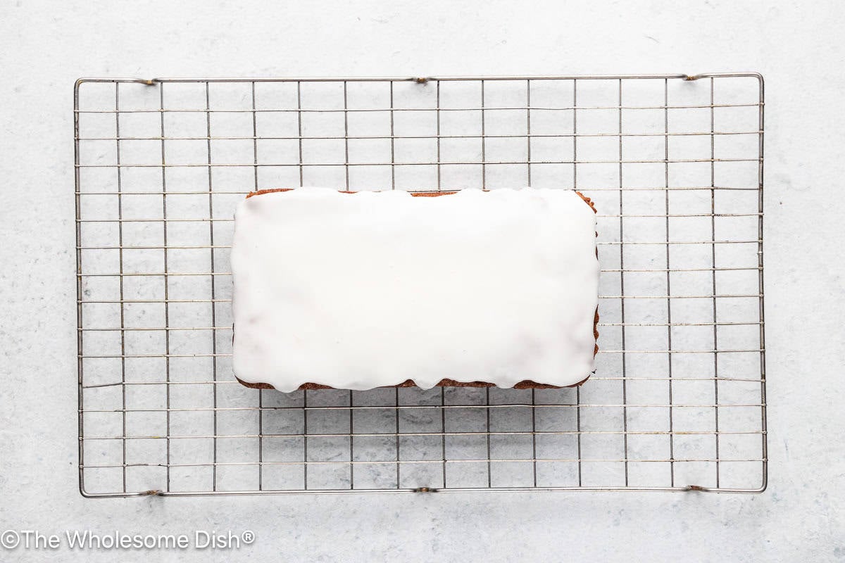 The lemon icing has been spread over the bread while the bread is on a wire rack.