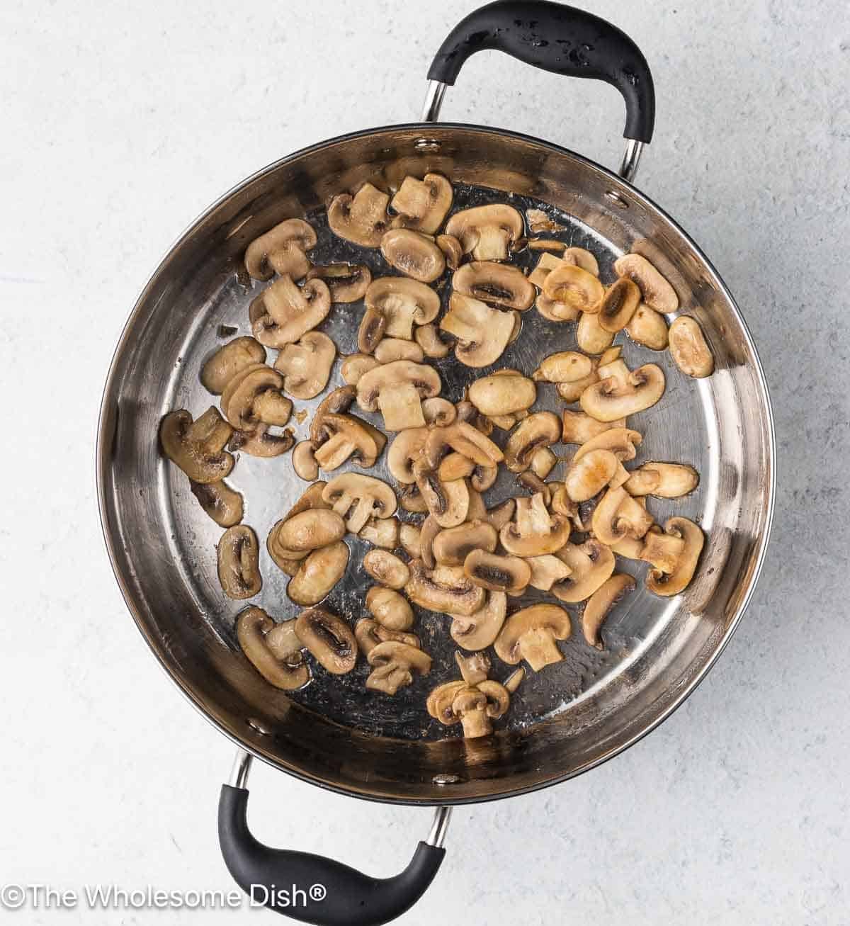 Mushrooms sautéing in a pot.