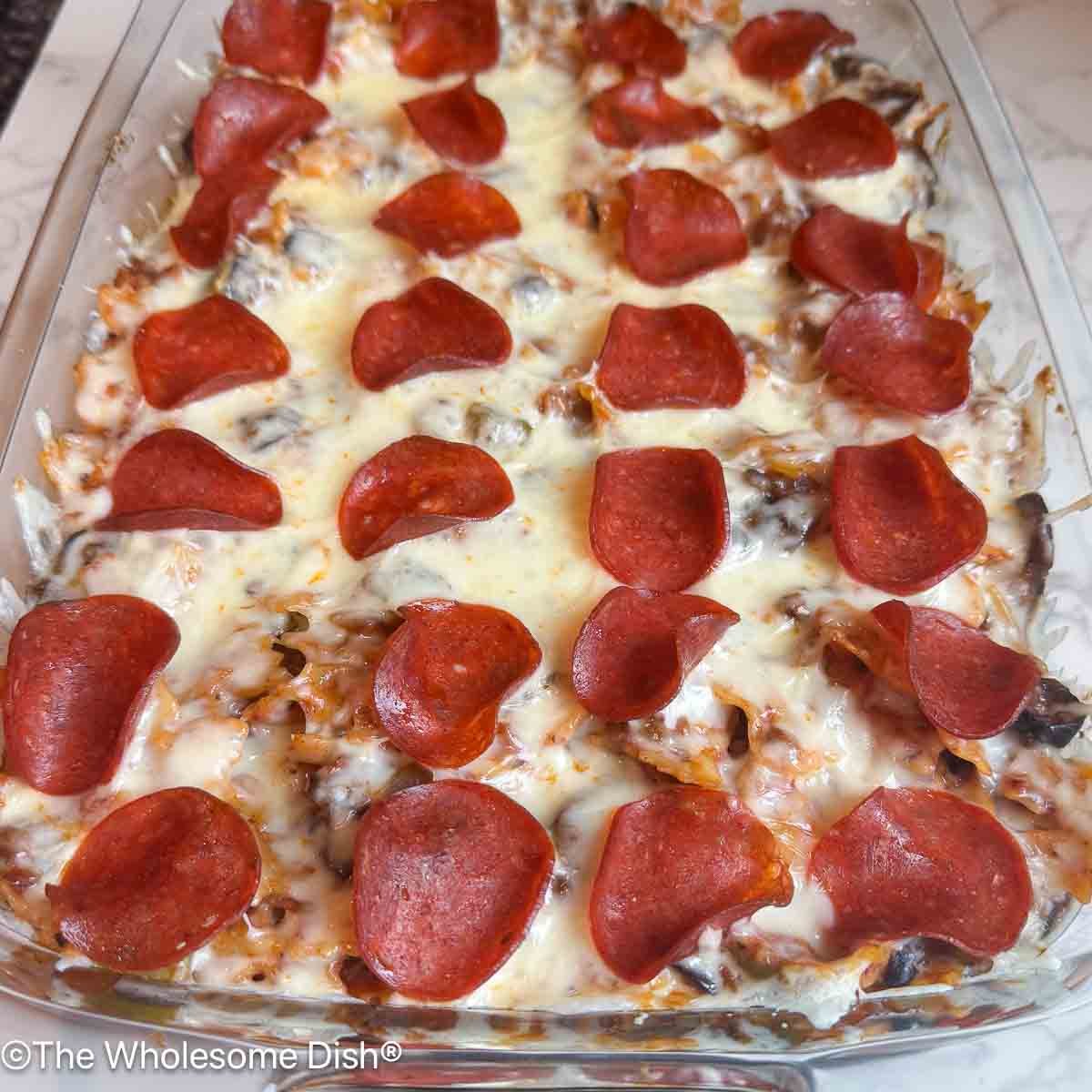 Pepperoni topped baked pizza pasta in a glass baking dish.