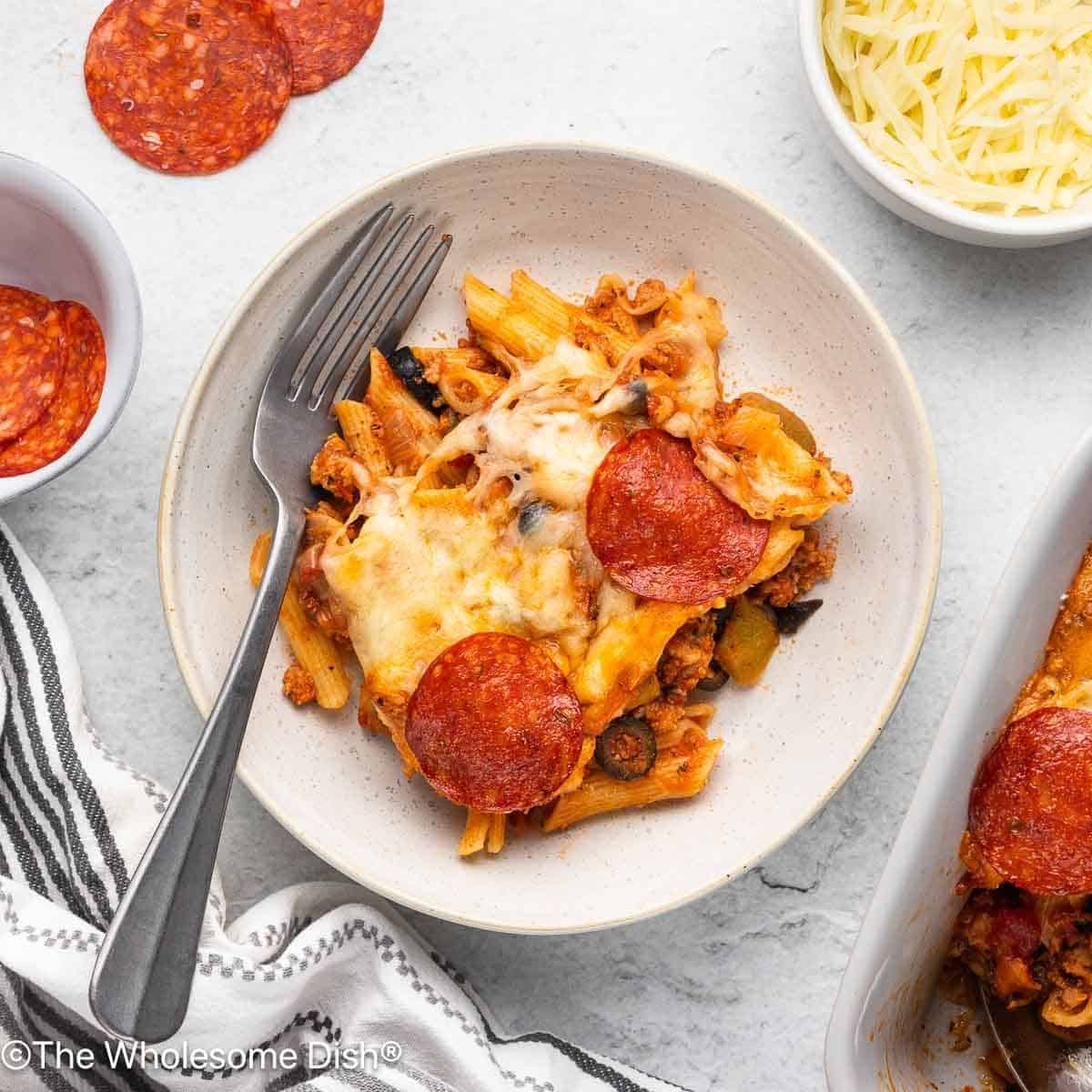 Supreme pizza baked pasta served on a white plate.