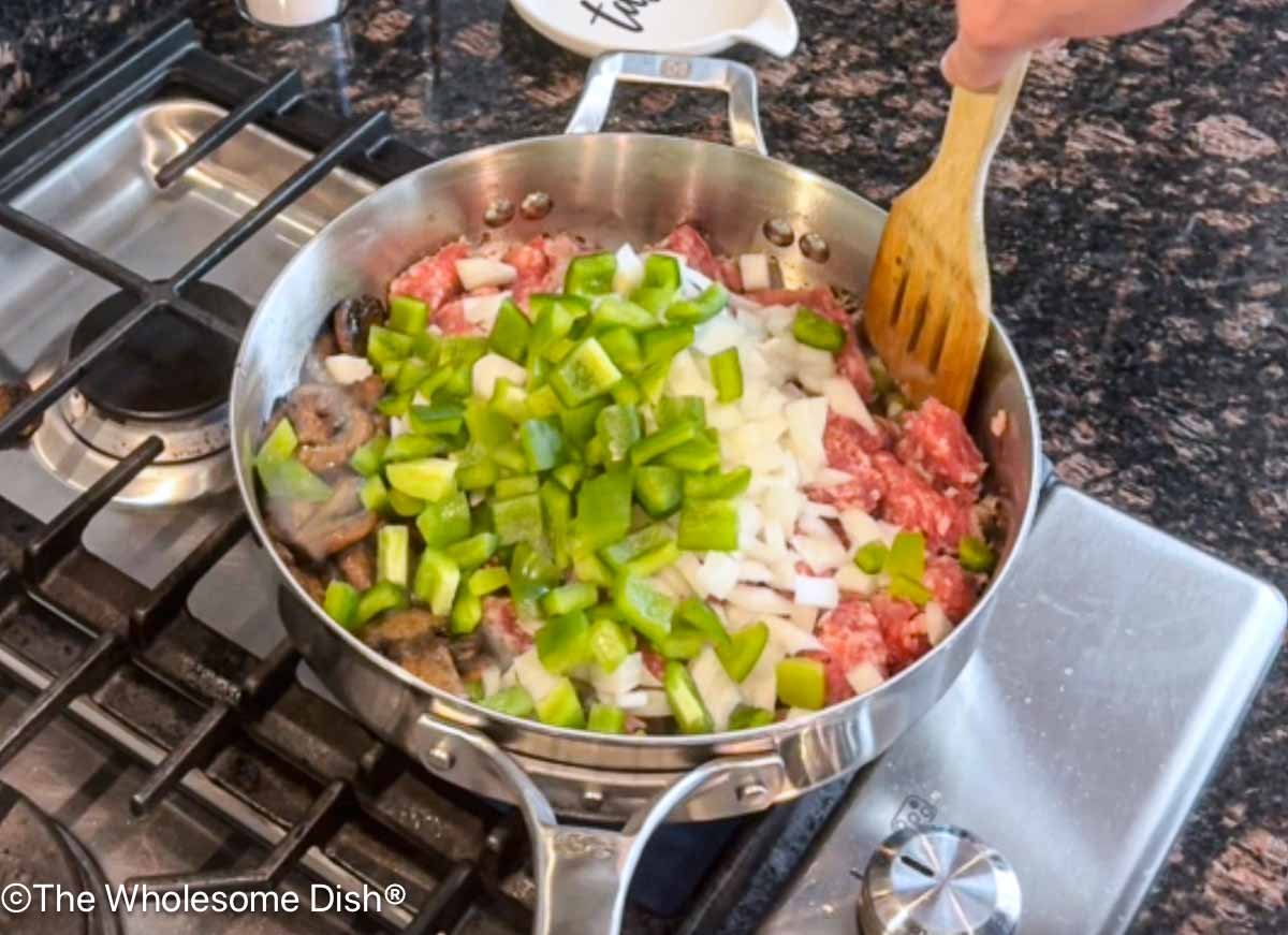 Chopped green bell peppers and yellow onions added to the skillet.