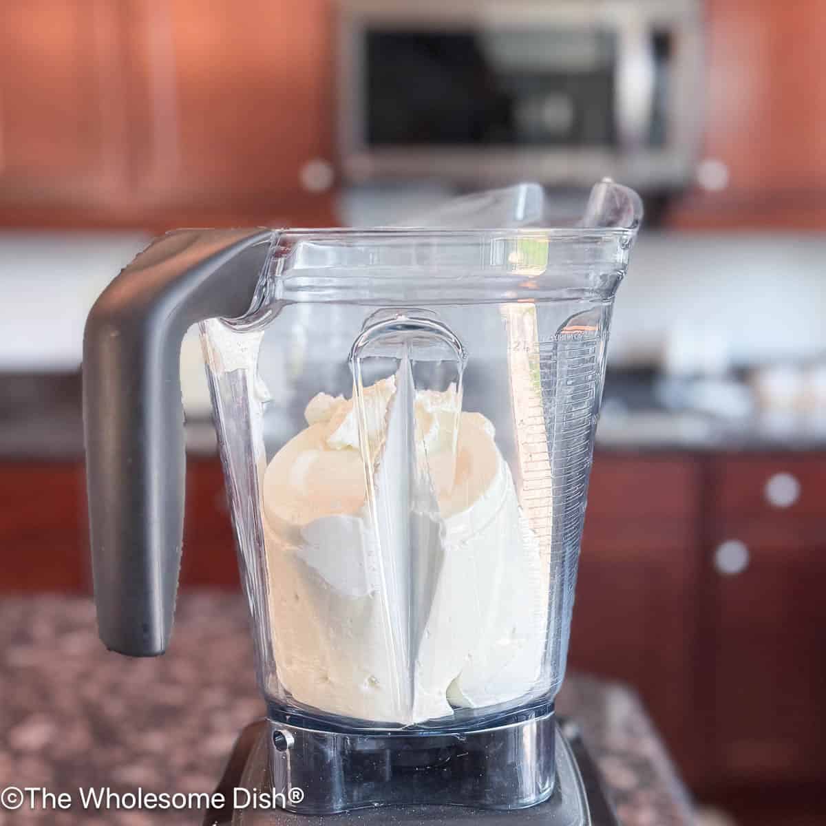 Blender with a tub of Greek yogurt poured into it.