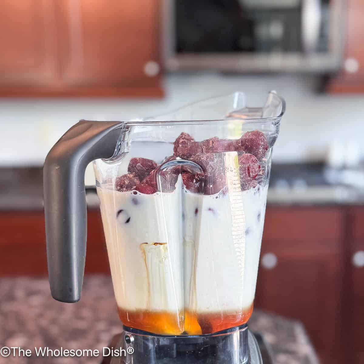 Milk, frozen cherries, and maple syrup have been added to the blender.