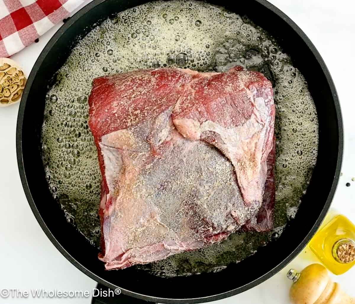 Chuck roast sautéing in a skillet.