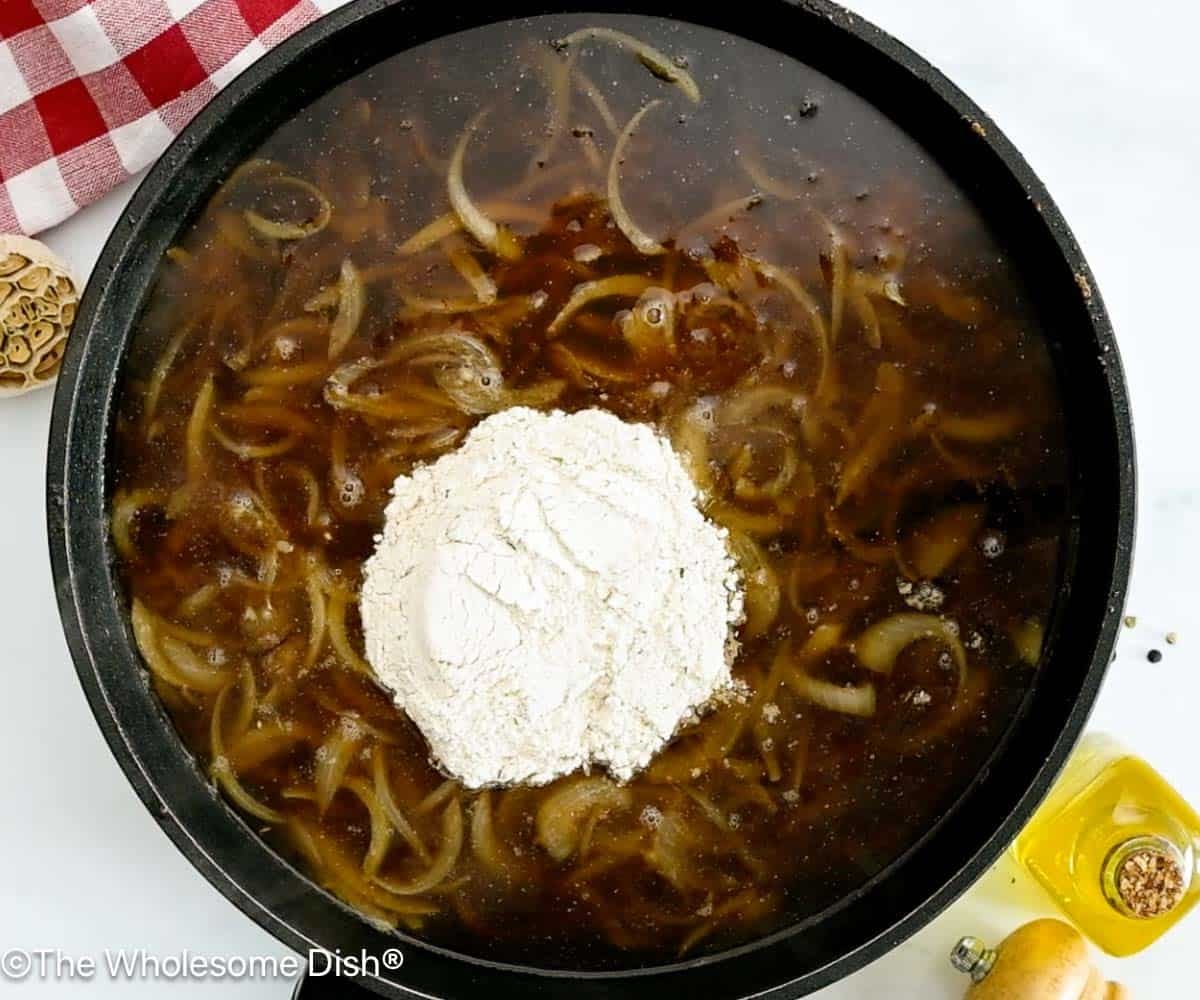 Skillet full of onions, beef broth, and au jus gravy mix.