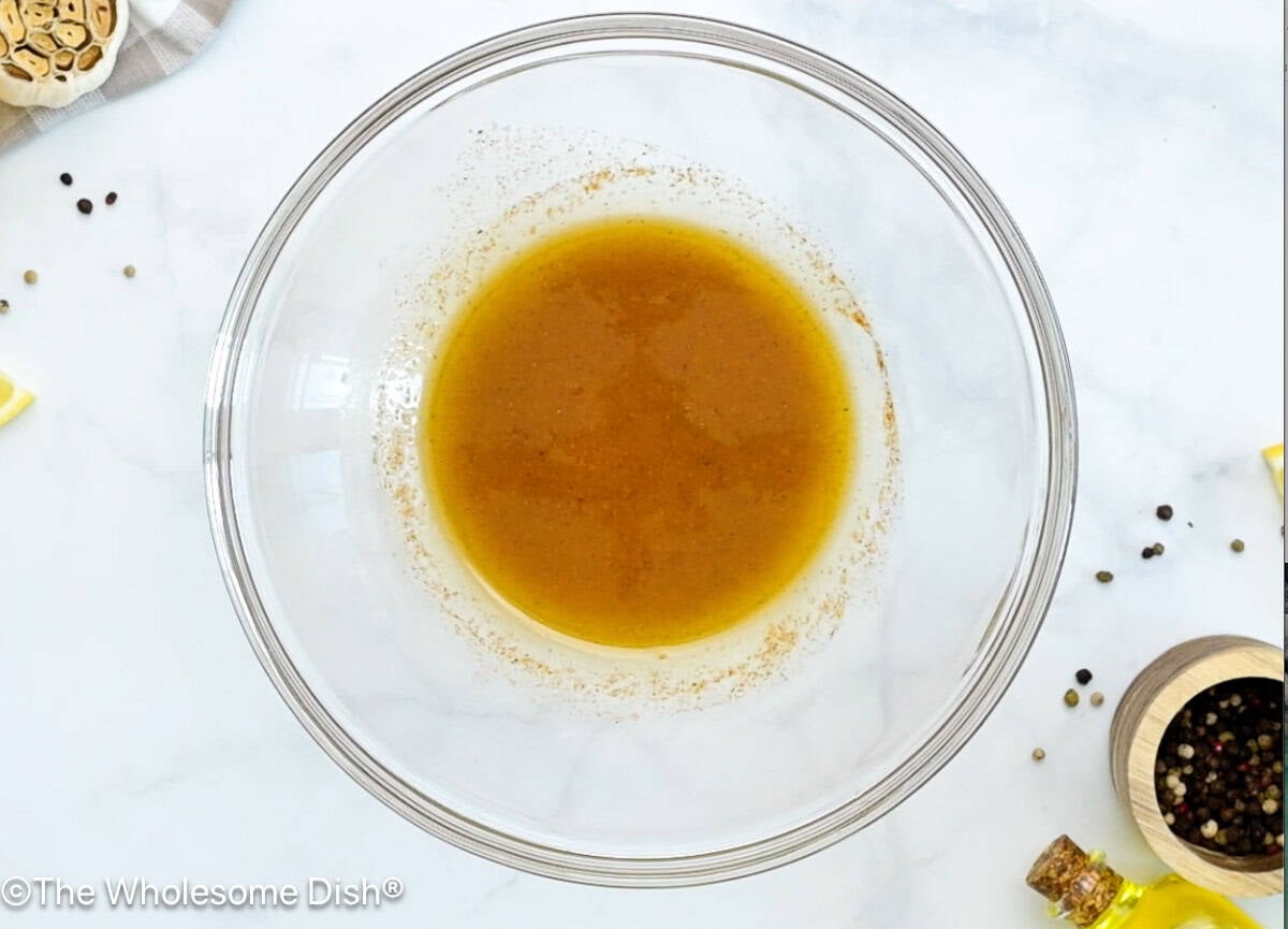 Miking bowl full of olive oil, lemon juice, and seasonings.