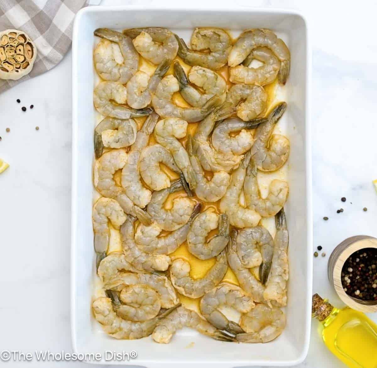Baking dish full of seasoned raw shrimp.