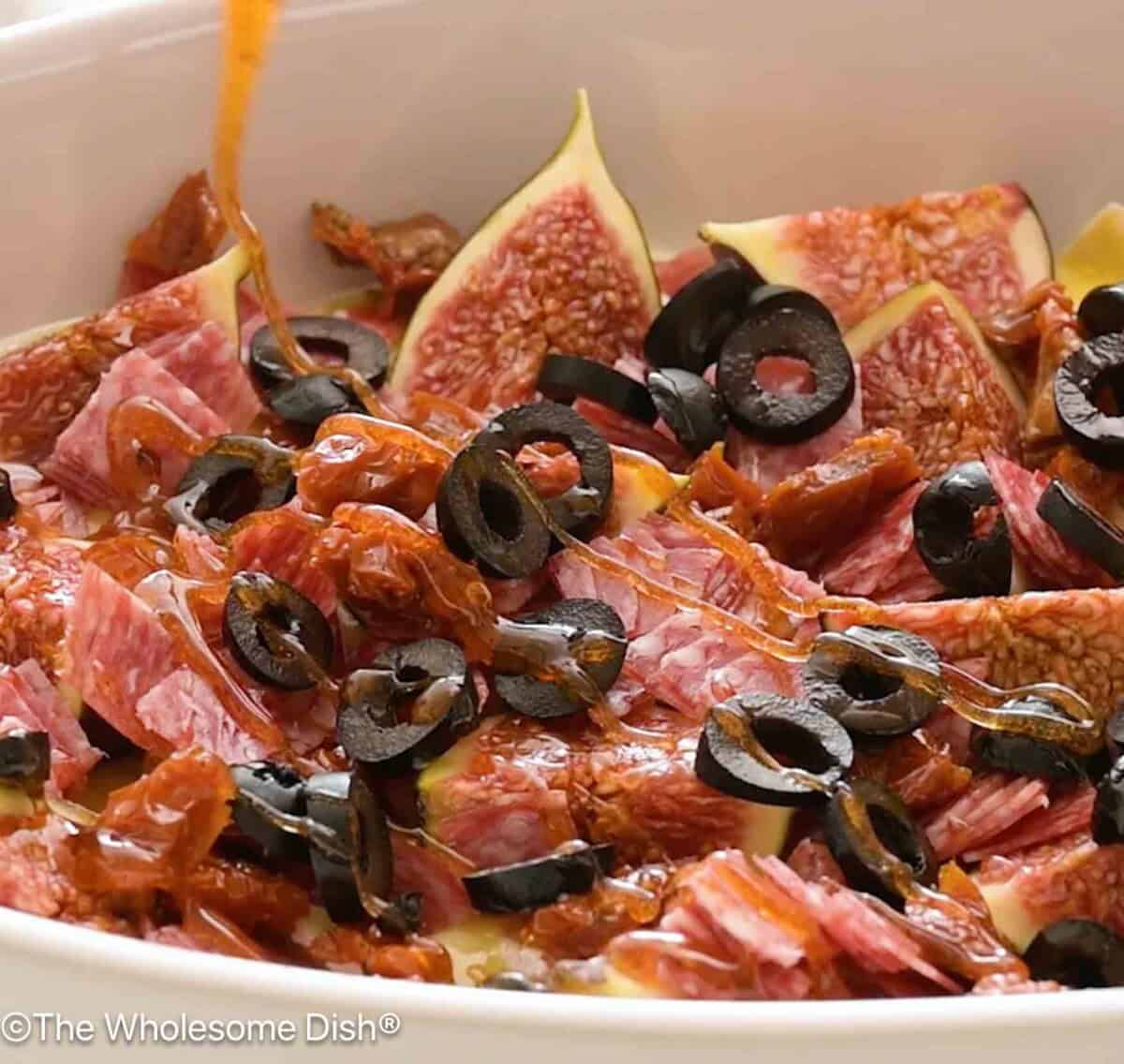 Hot honey being drizzles over charcuterie dip.
